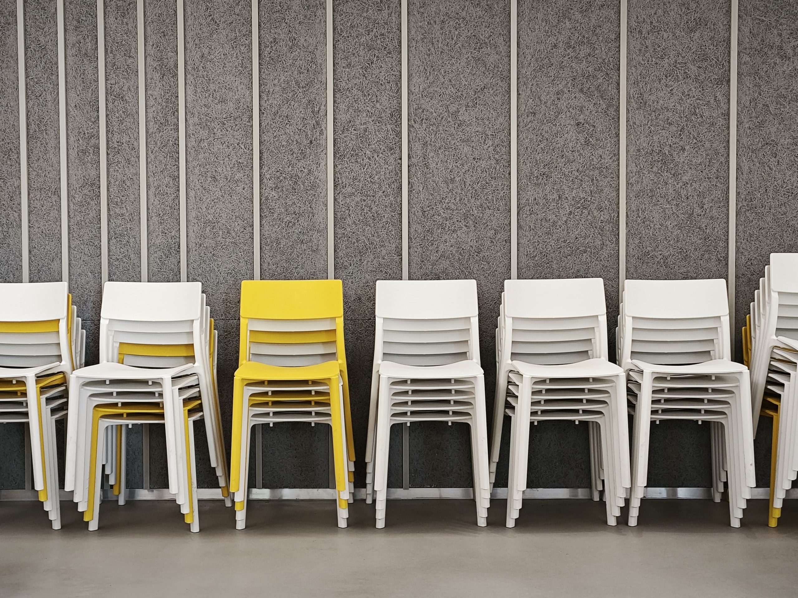 Office furniture stacking chairs neatly stacked together in a conference room, showing space-saving seating design.
